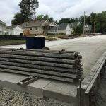A pile of steel beams on top of a recently paved street