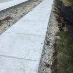 Long slab of cement sidewalk leading to more construction